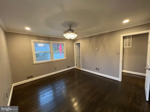 an empty room with wooden floor chandelier and windows