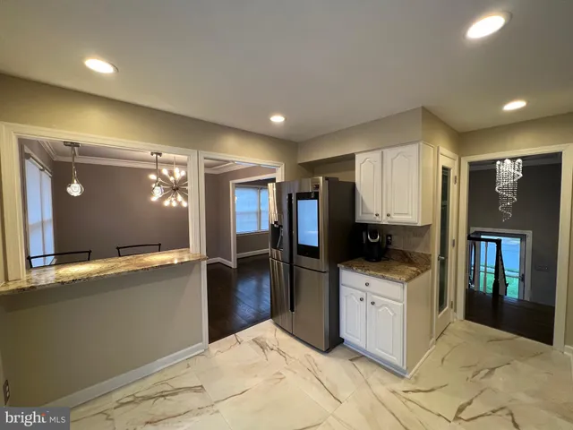 a large kitchen with a large counter top a sink stainless steel appliances and cabinets