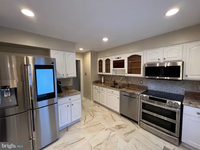 a kitchen with stainless steel appliances granite countertop a refrigerator and a stove top oven