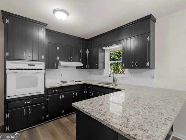 a kitchen with a sink and a stove top oven with wooden floor
