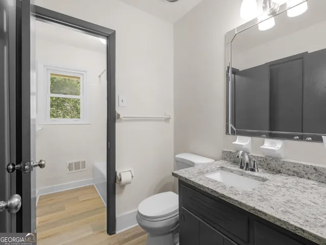 a bathroom with a granite countertop sink toilet and mirror
