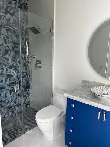a bathroom with a granite countertop toilet sink and mirror