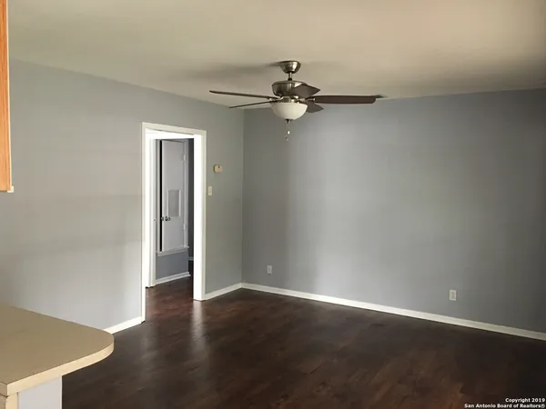 an empty room with wooden floor closet and windows