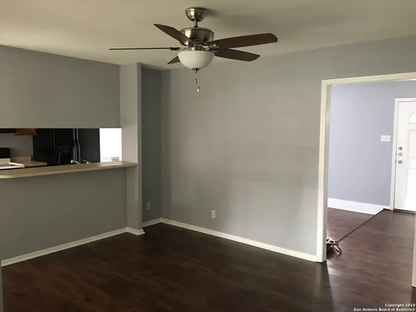 an empty room with wooden floor fan and windows