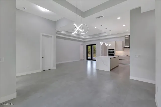 a view of an empty room and a kitchen with a sink
