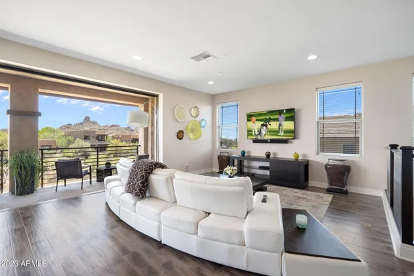 a view of a dining room and livingroom with furniture wooden floor a rug a fireplace and a chandelier