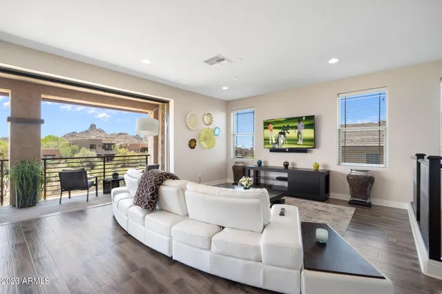 a view of a dining room and livingroom with furniture wooden floor a rug a fireplace and a chandelier