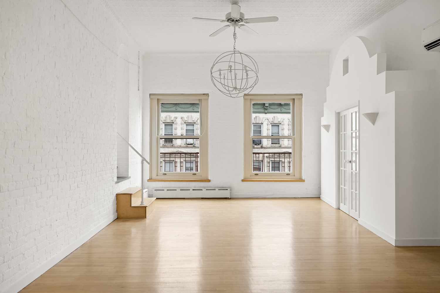 169 Spring Street, Unit 5W Manhattan, NY 10012 - Photo 12 of 20 a view of an empty room with wooden floor and a window