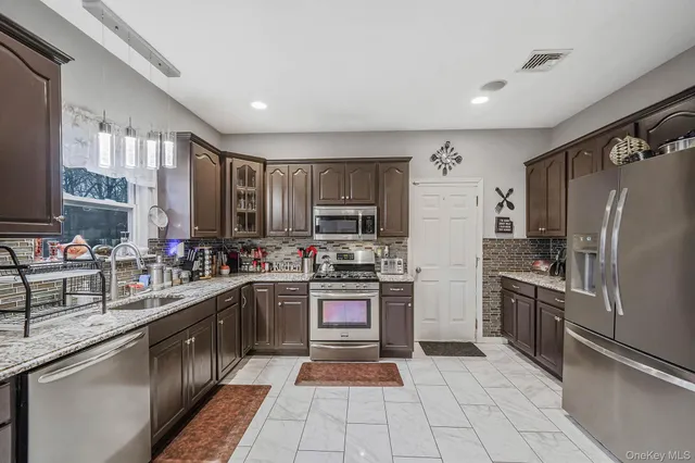 a kitchen with stainless steel appliances granite countertop a refrigerator and a stove top oven