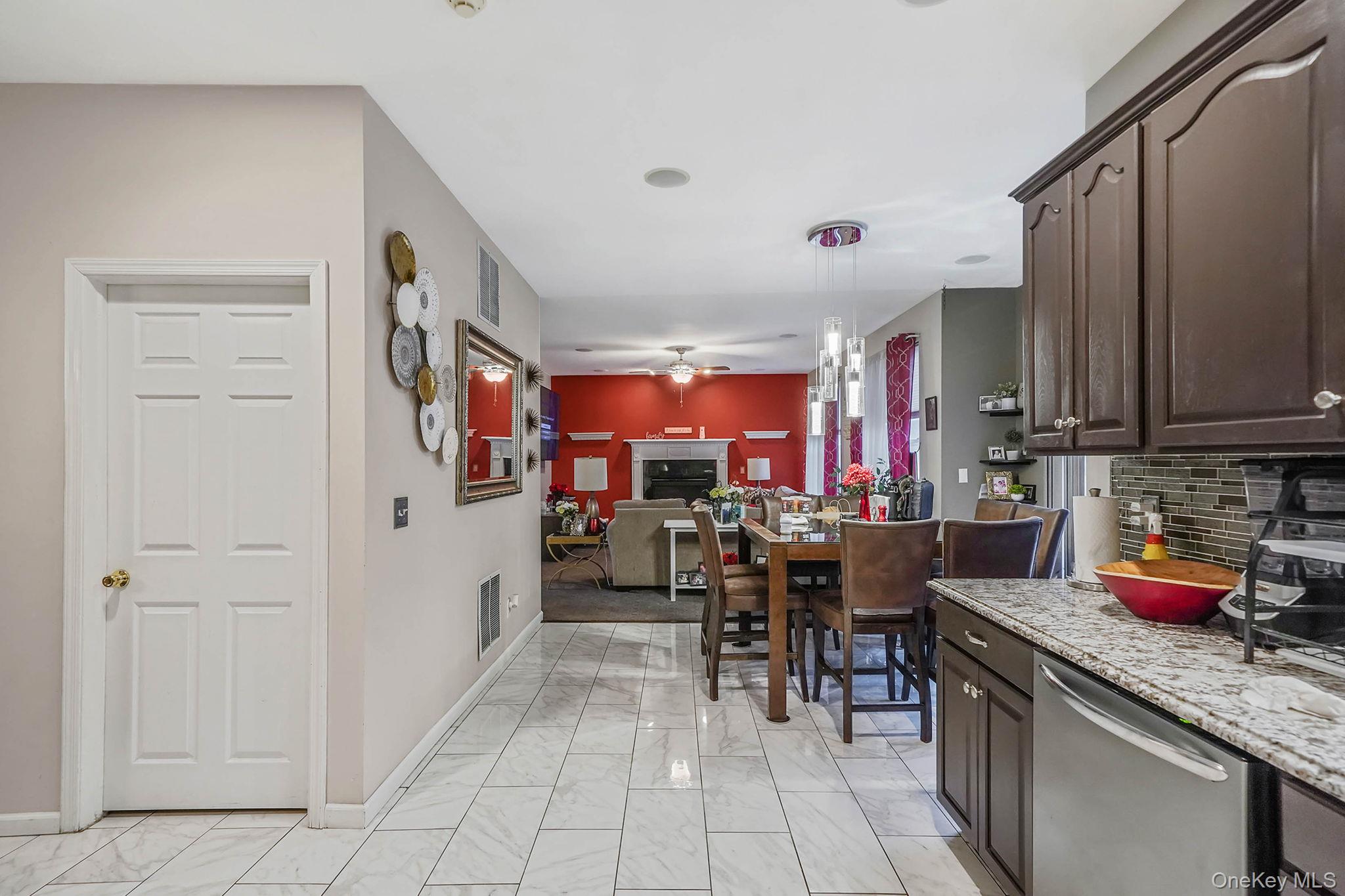 9 Paddock Lane Medford, NY 11763 - Photo 15 of 49 Kitchen featuring dark brown cabinetry, backsplash, hanging light fixtures, dishwasher, and light marble finish floors