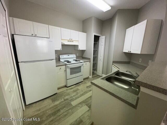5692 Star Rush Drive, Unit 106 Melbourne, FL 32940 - Photo 4 of 16 a kitchen with a refrigerator a stove a sink and white cabinets
