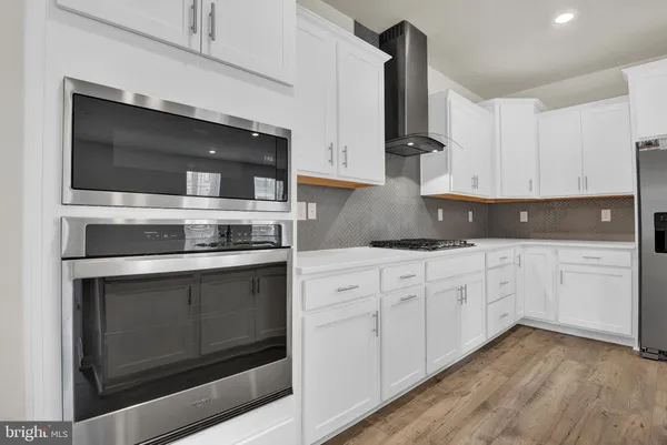 a kitchen with stainless steel appliances white cabinets and a fireplace