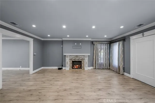 a view of an empty room with wooden floor fireplace and a window