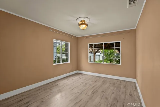 a view of empty room with wooden floor and window