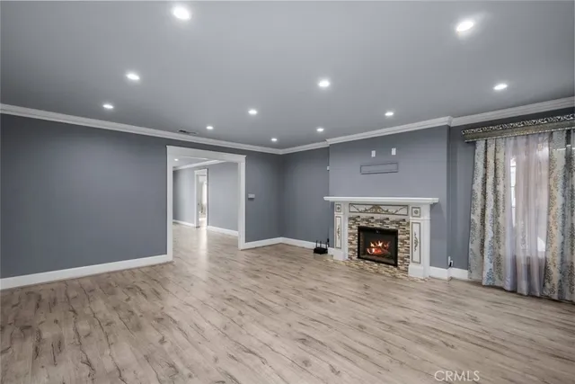 an empty room with wooden floor fireplace and windows
