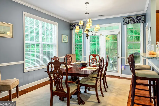 a dining room filled chandelier and wooden furniture