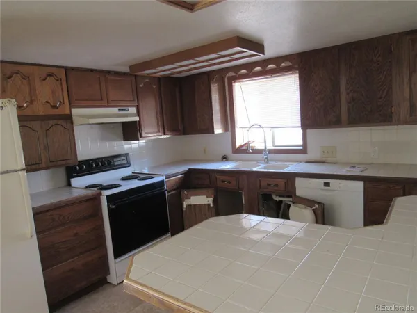a kitchen with kitchen island granite countertop a sink stove and refrigerator