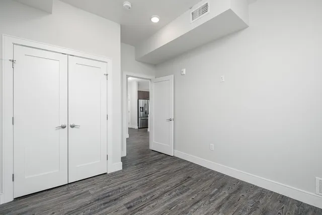 a front view of a building with lot of cars and trees