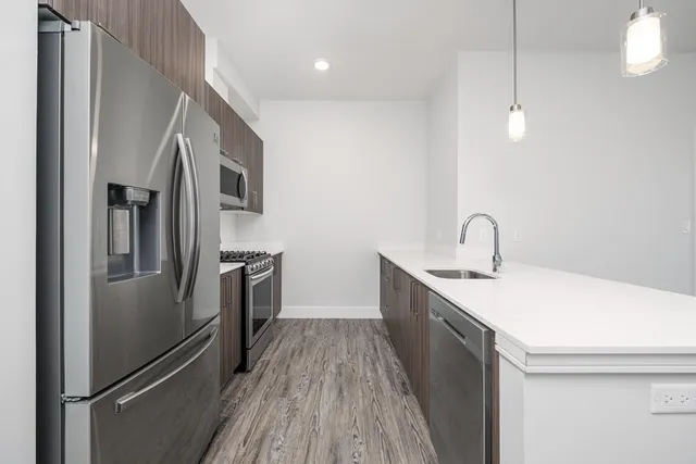a kitchen with sink a refrigerator and wooden floor