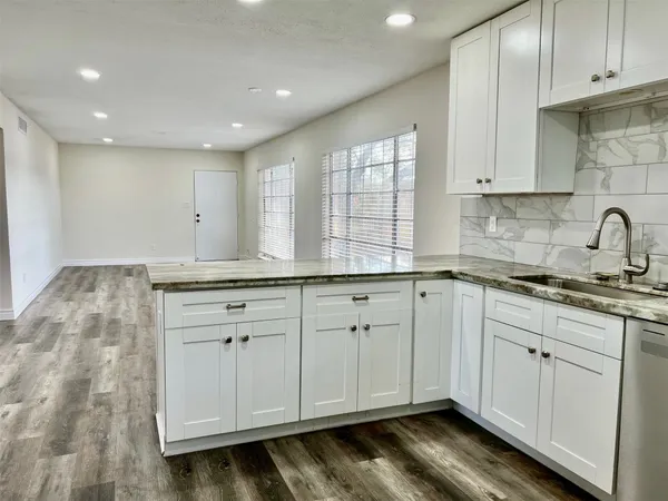 a kitchen with granite countertop white cabinets and stainless steel appliances