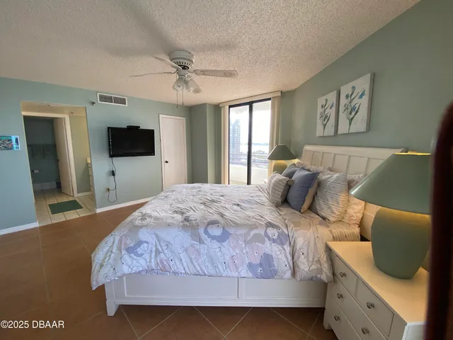 a bedroom with a large bed and a flat tv screen on dresser