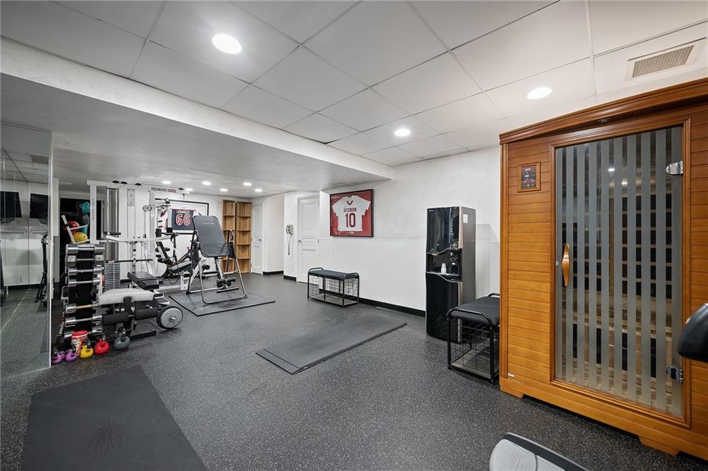 898 Persimmon Road Sewickley, PA 15143 - Photo 41 of 50 The lower-level gym is a bright, expansive space with high ceilings, recessed lighting, and mirrored walls that enhance its open feel. Durable flooring provides a polished, modern look and an inviting environment for wellness and relaxation.