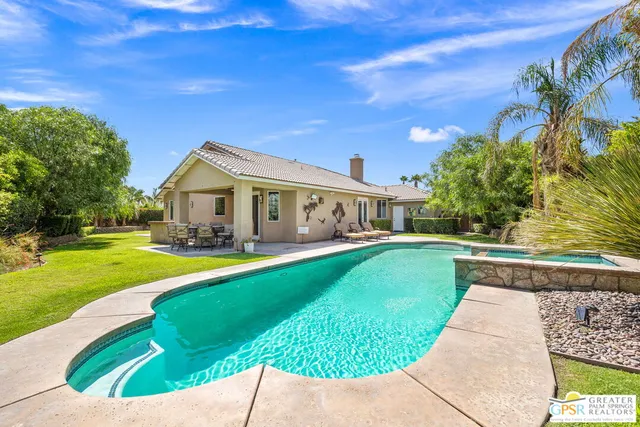 a view of an house with swimming pool lawn chairs and a yard