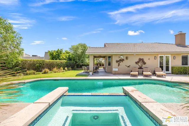 a view of a swimming pool with lawn chairs and a big yard