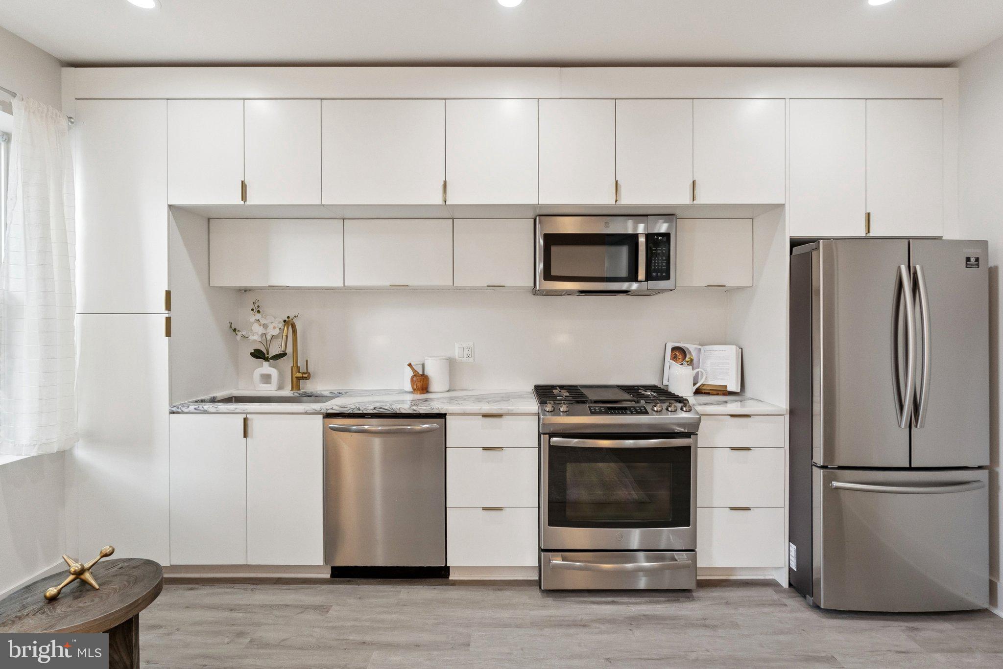 839 Kennedy Street Northwest, Unit 105 Washington, DC 20011 - Photo 4 of 21 a kitchen with stainless steel appliances a stove a microwave and a refrigerator