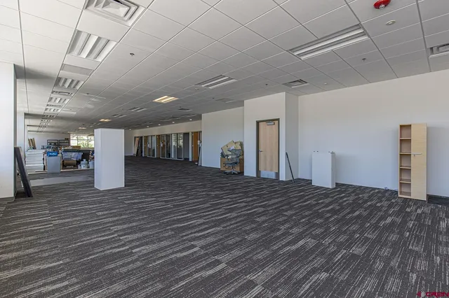 a view of a hallway to an empty room with wooden floor and a window