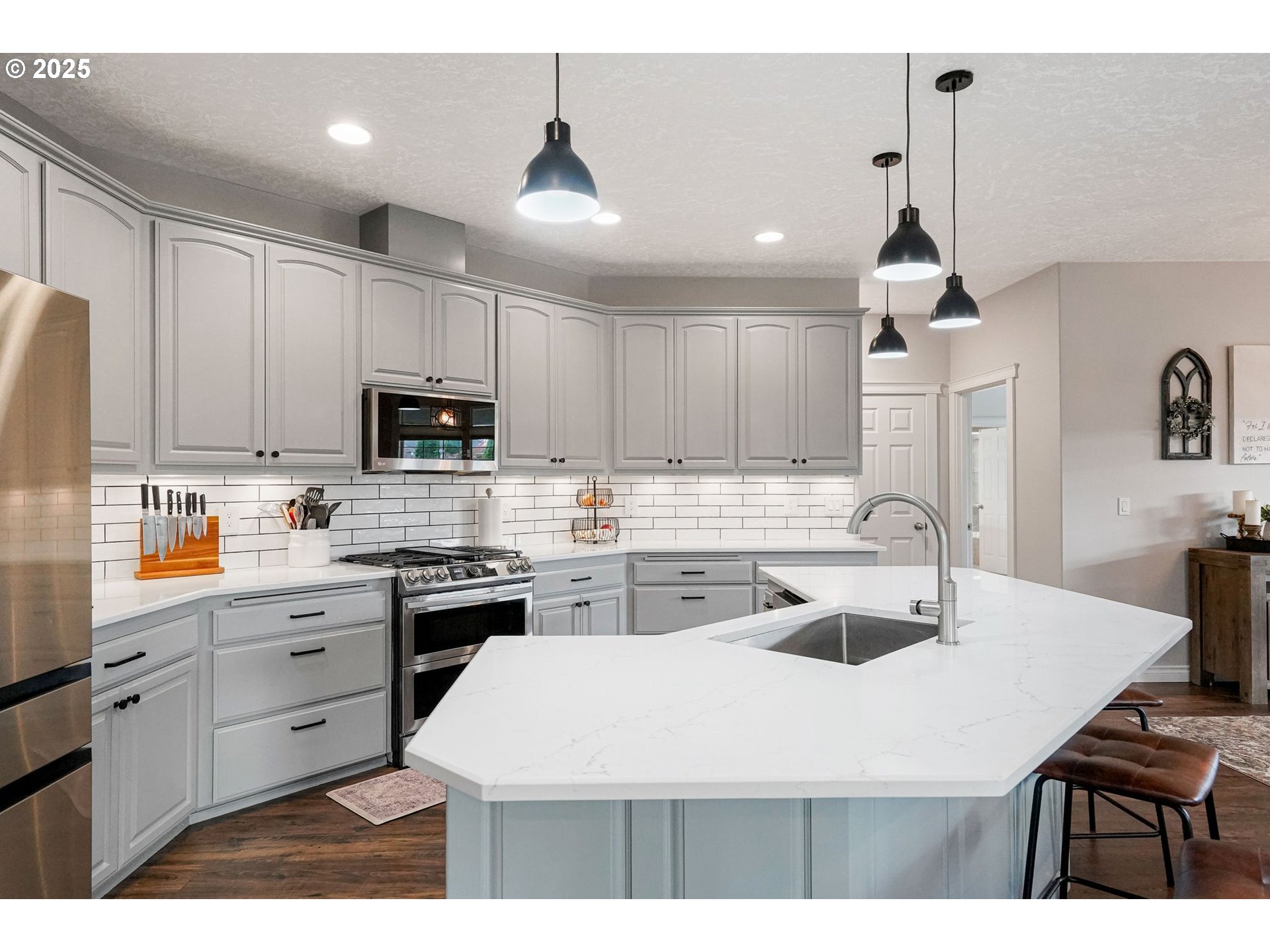 3208 54th Avenue Northeast Albany, OR 97321 - Photo 27 of 43 a kitchen with stainless steel appliances a sink a stove a refrigerator a center island and cabinets