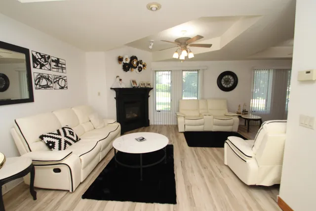 a living room with couches a fireplace and a dining table with wooden floor
