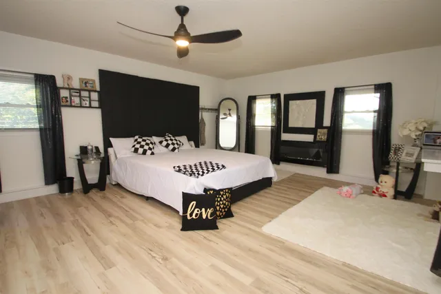 a living room with a bed furniture flat screen tv and a large window
