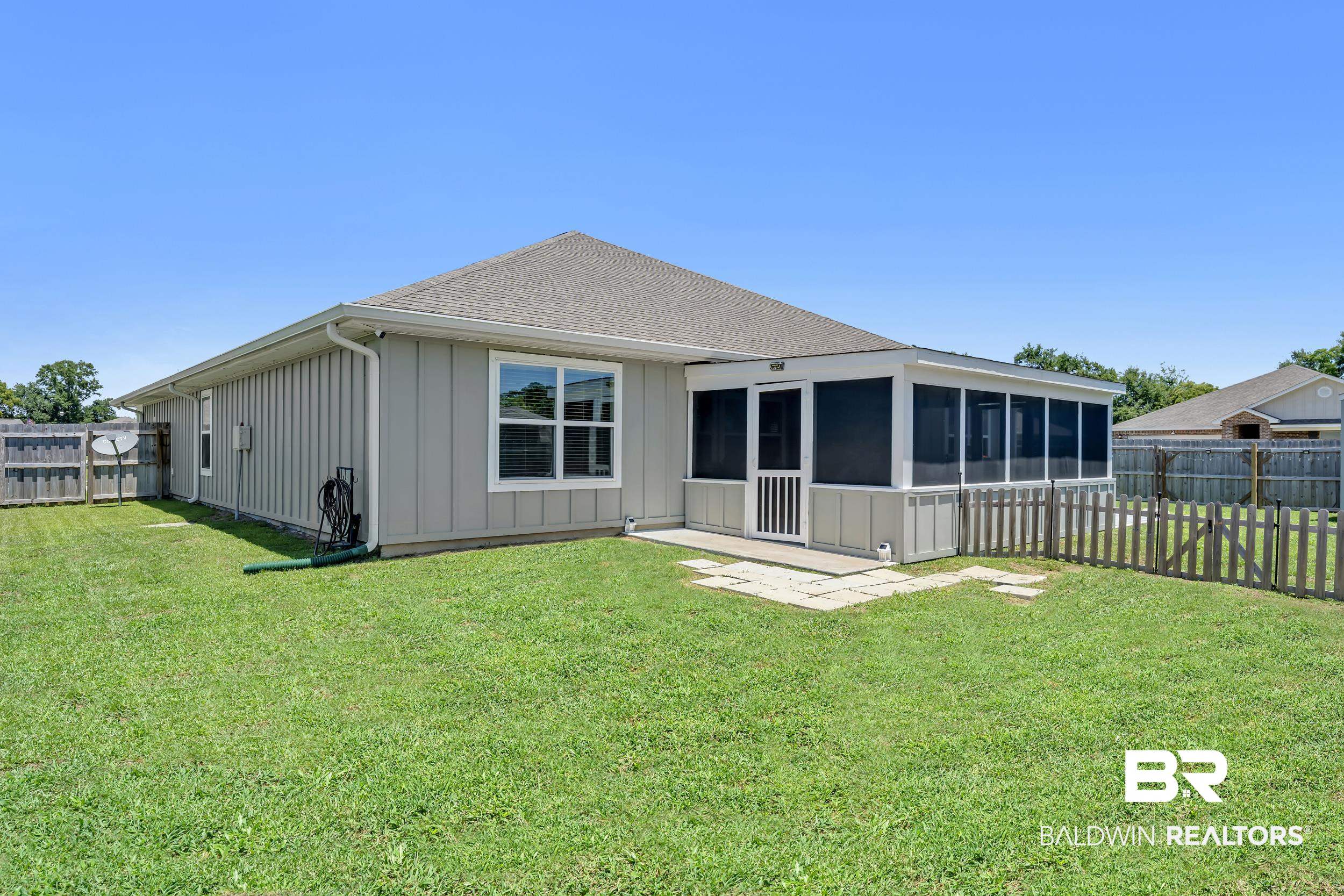 24271 Ringneck Loop Elberta, AL 36530 - Photo 41 of 44 Spacious backyard featuring a screened-in porch, privacy fencing, a picket fence, and a stone patio