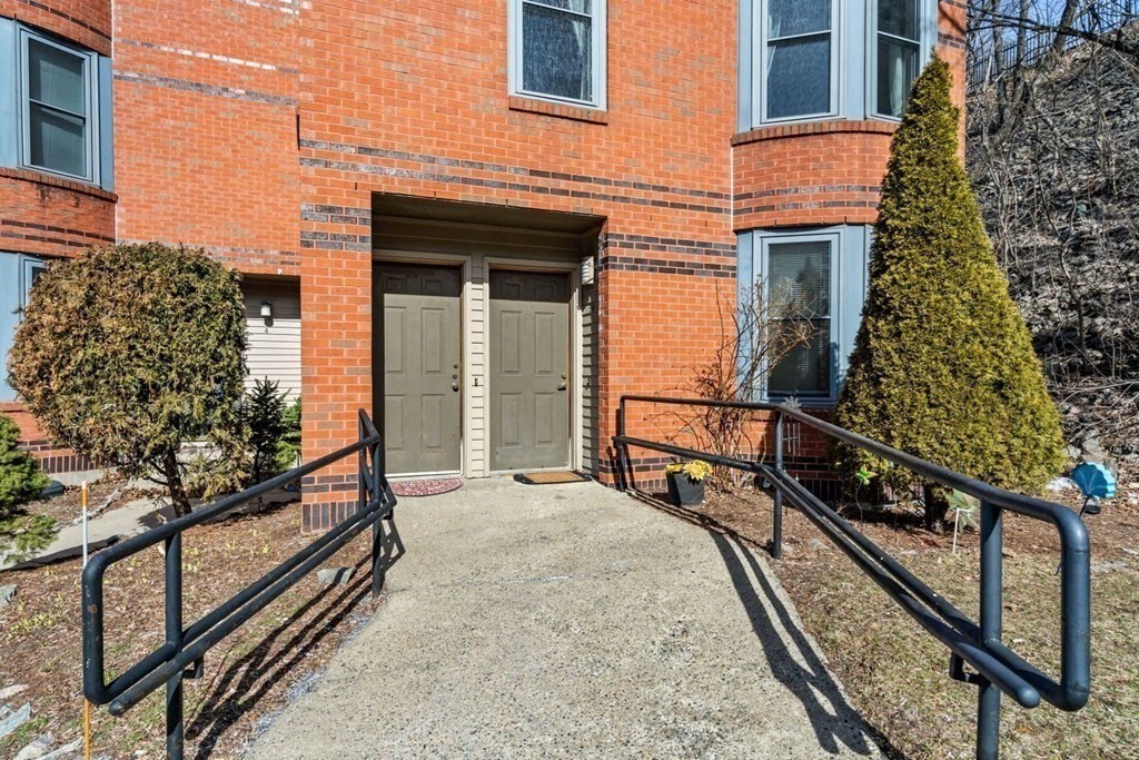 5 B Eileen Circle, Unit 11 Boston, MA 02130 - Photo 18 of 19 a view of a balcony with two chairs and a potted plant on a brick wall