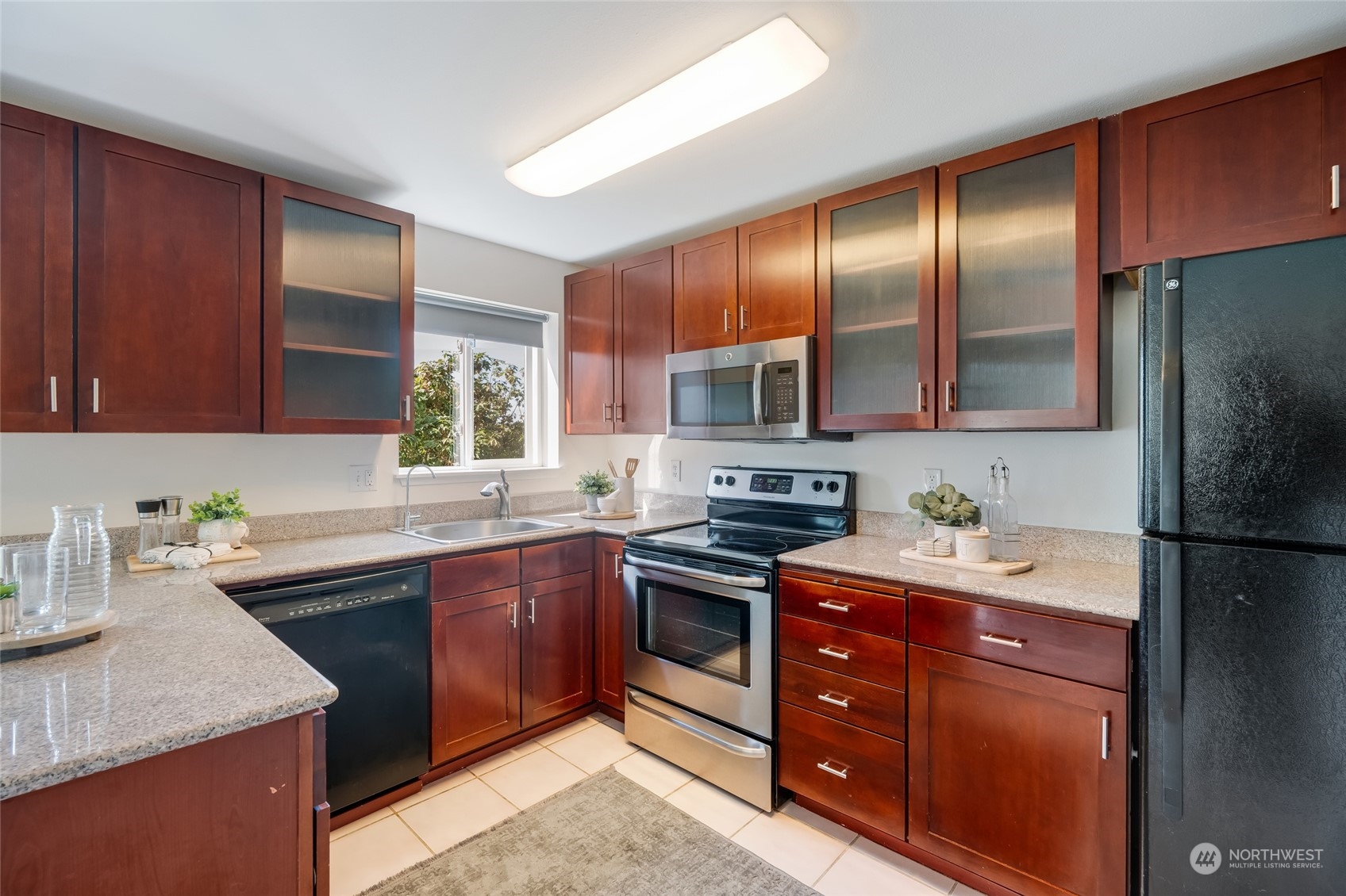1110 West Howe Street, Unit 304 Seattle, WA 98119 - Photo 6 of 24 a kitchen with stainless steel appliances granite countertop wooden cabinets sink stove and refrigerator