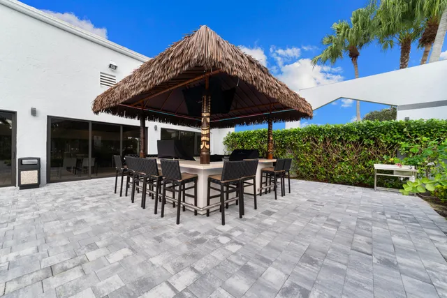 a view of a patio with table and chairs under an umbrella with a barbeque