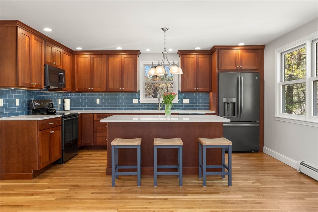 336 Sharpners Pond Road North Andover, MA 01845 - Photo 10 of 42 a kitchen with stainless steel appliances granite countertop a refrigerator a sink dishwasher a stove and a dining table with wooden floor