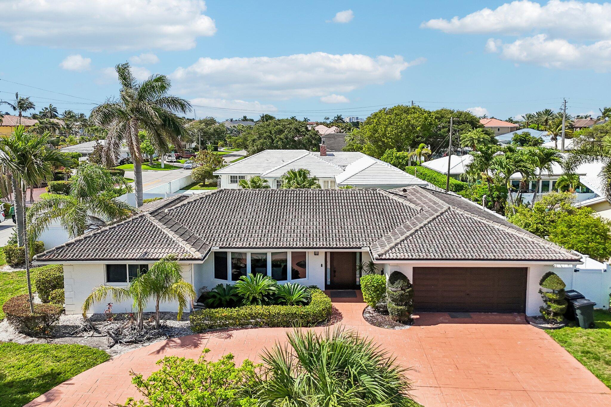 2940 Northeast 39th Court Lighthouse Point, FL 33064 - Photo 1 of 42 a front view of a house with a yard and potted plants