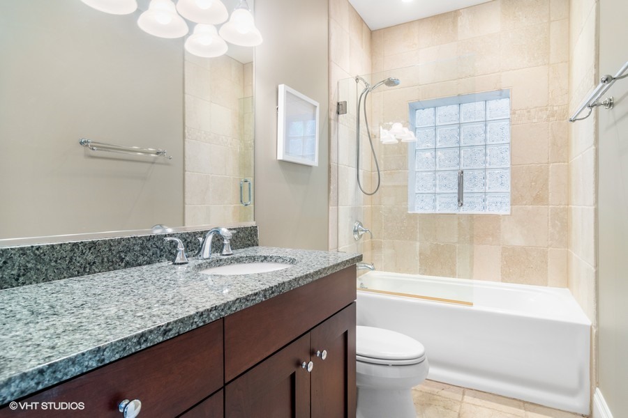 2002 West Barry Avenue Chicago, IL 60618 - Photo 16 of 25 a bathroom with a granite countertop sink a toilet a mirror and shower