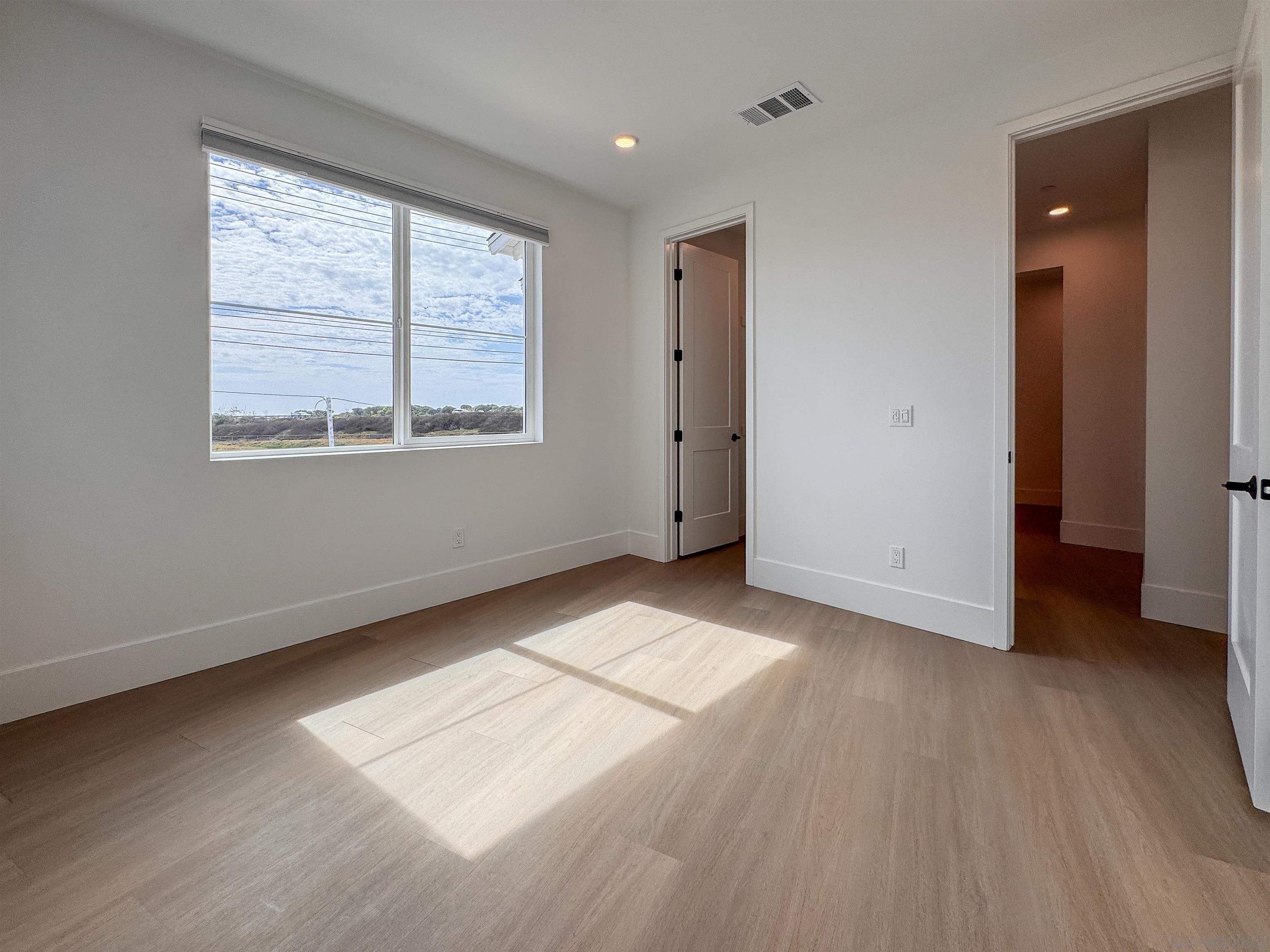 7290 Ponto Drive, Unit 7302 Carlsbad, CA 92011 - Photo 35 of 54 a view of an empty room with wooden floor and a window