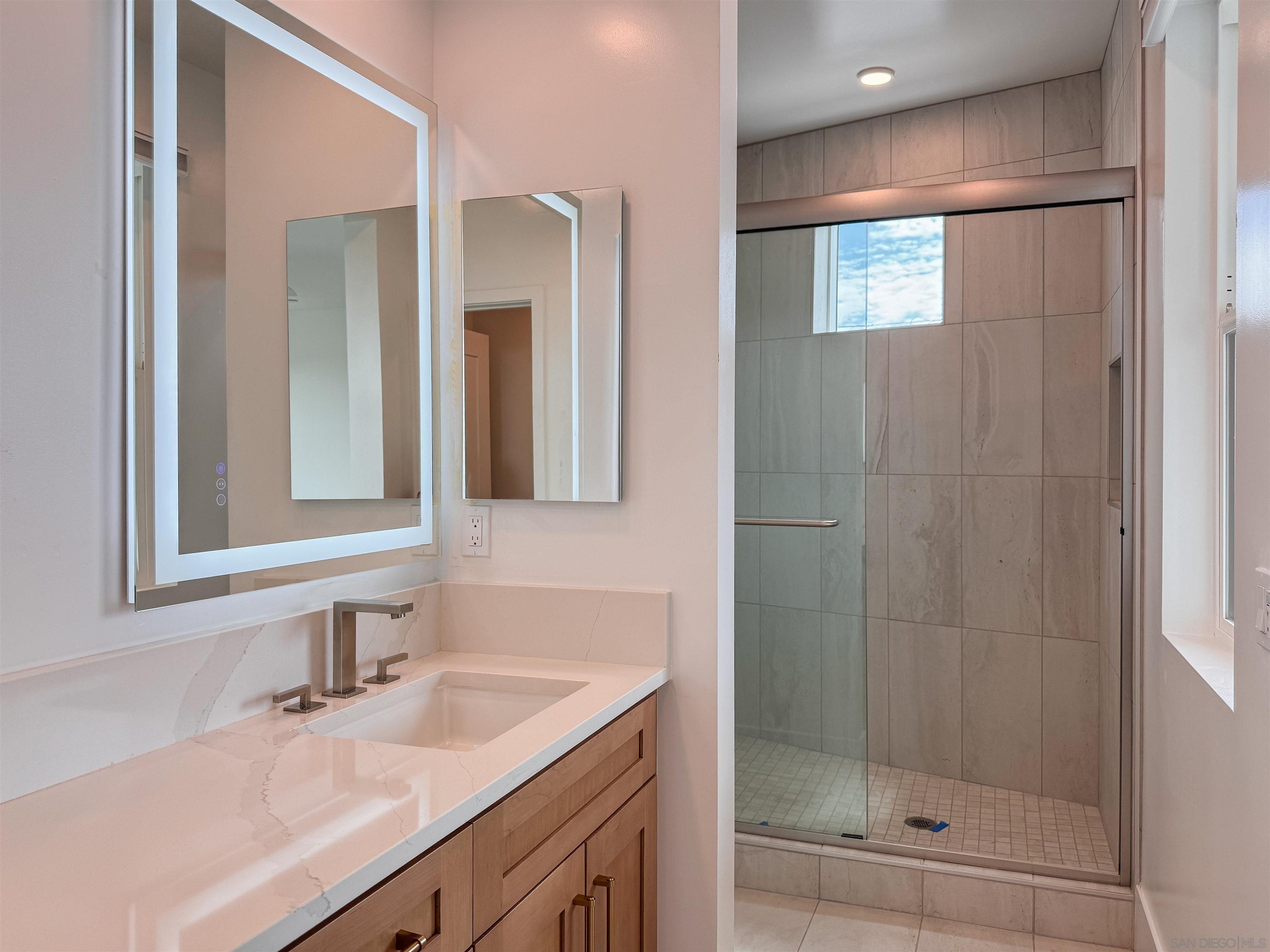 7290 Ponto Drive, Unit 7302 Carlsbad, CA 92011 - Photo 44 of 54 a bathroom with a shower sink and mirror