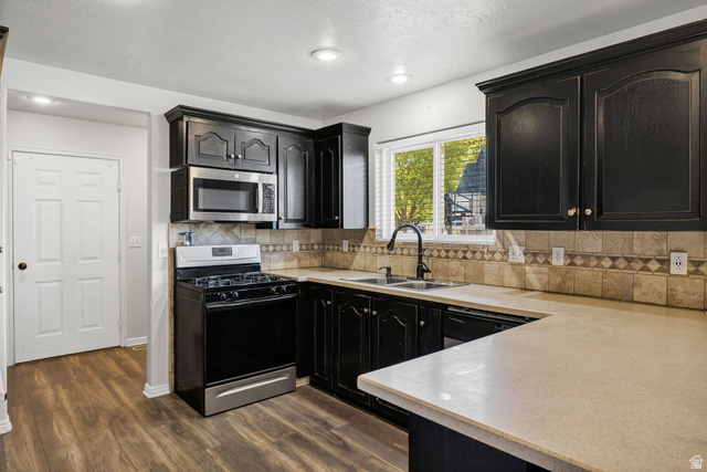 892 East 400 South Smithfield, UT 84335 - Photo 10 of 44 Kitchen featuring black gas range oven, light countertops, dark cabinets, dark wood-style flooring, and stainless steel microwave