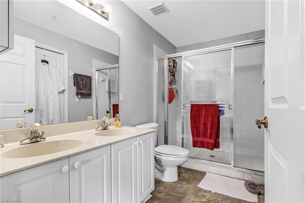 9175 Celeste Drive, Unit 2202 Naples, FL 34113 - Photo 18 of 27 a bathroom with a sink vanity mirror and toilet