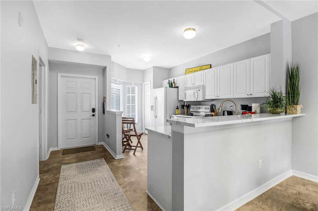 9175 Celeste Drive, Unit 2202 Naples, FL 34113 - Photo 4 of 27 a kitchen with stainless steel appliances white cabinets and a refrigerator