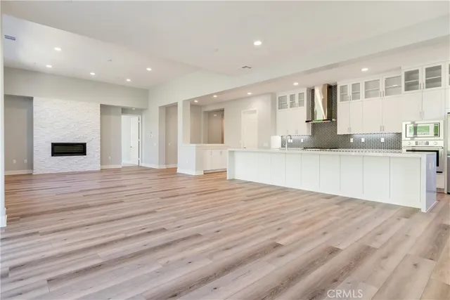 a view of a kitchen with kitchen island granite countertop wooden floor stainless steel appliances and cabinets