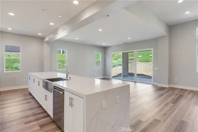 a large kitchen with stainless steel appliances a large counter top a large window and wooden floor
