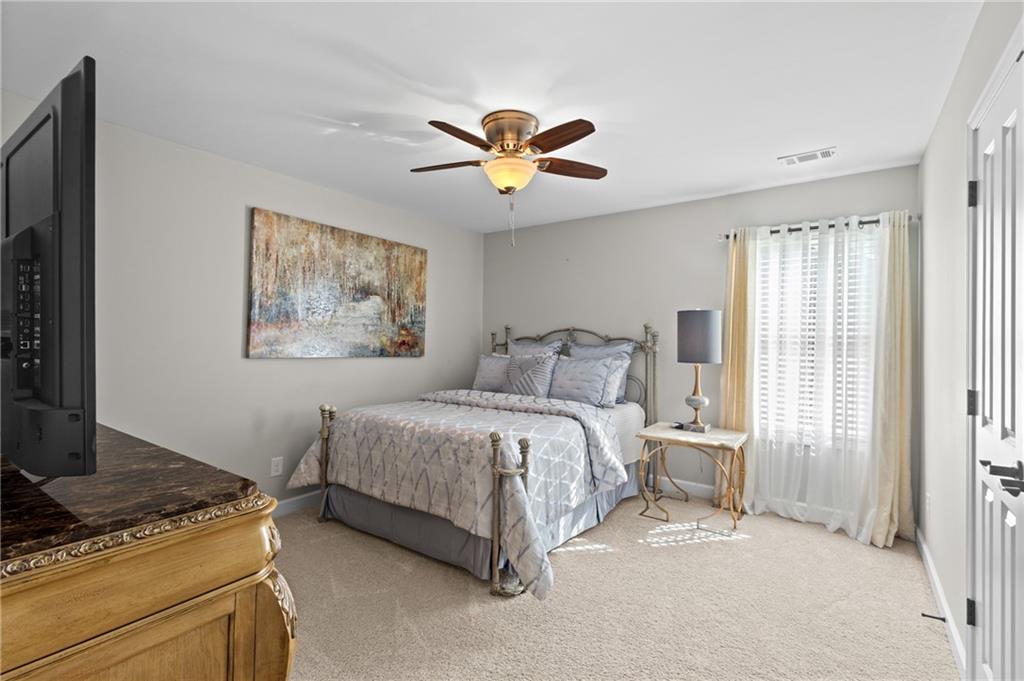 4469 Tacoma Trace Suwanee, GA 30024 - Photo 24 of 62 a bedroom with a bed and a chandelier