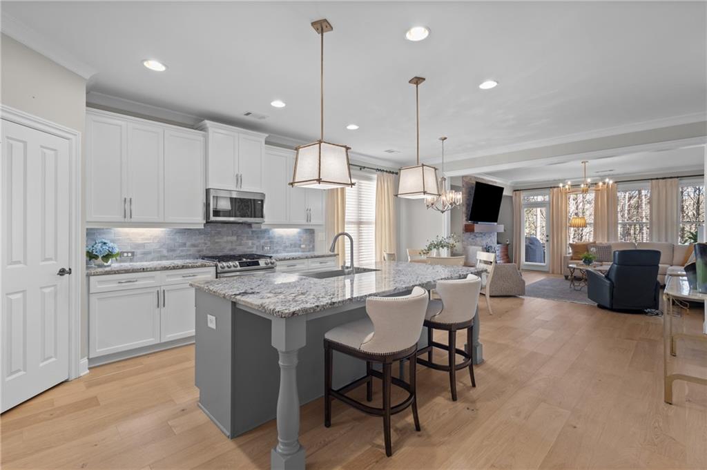 4469 Tacoma Trace Suwanee, GA 30024 - Photo 3 of 62 a large kitchen with kitchen island granite countertop lots of white cabinets appliances and dining table