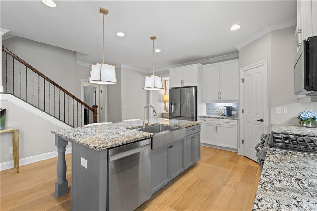 4469 Tacoma Trace Suwanee, GA 30024 - Photo 5 of 62 a kitchen with stainless steel appliances kitchen island granite countertop a table chairs sink and cabinets